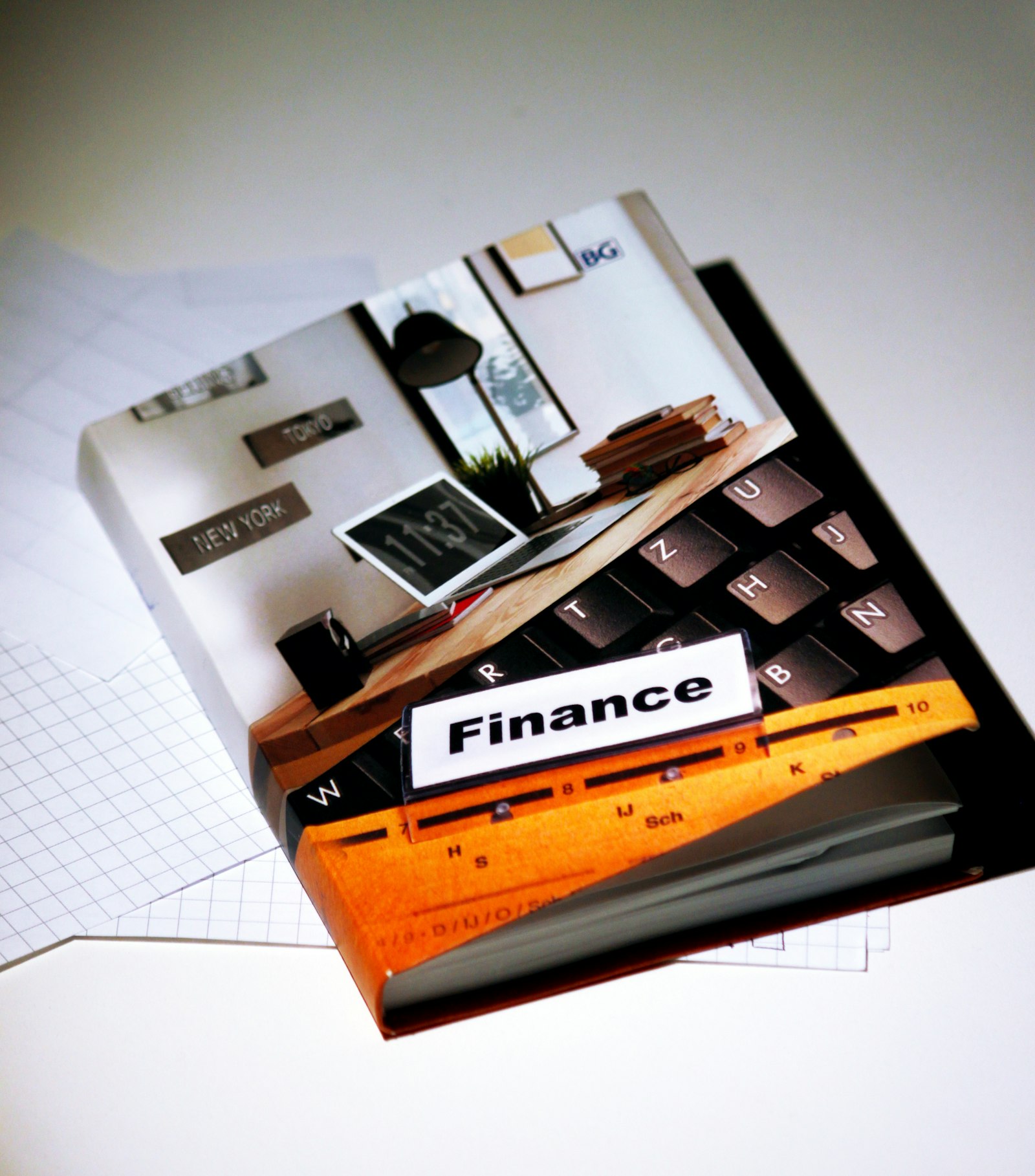 A finance book overlaid with a calculator keypad and graph-paper financial sheets